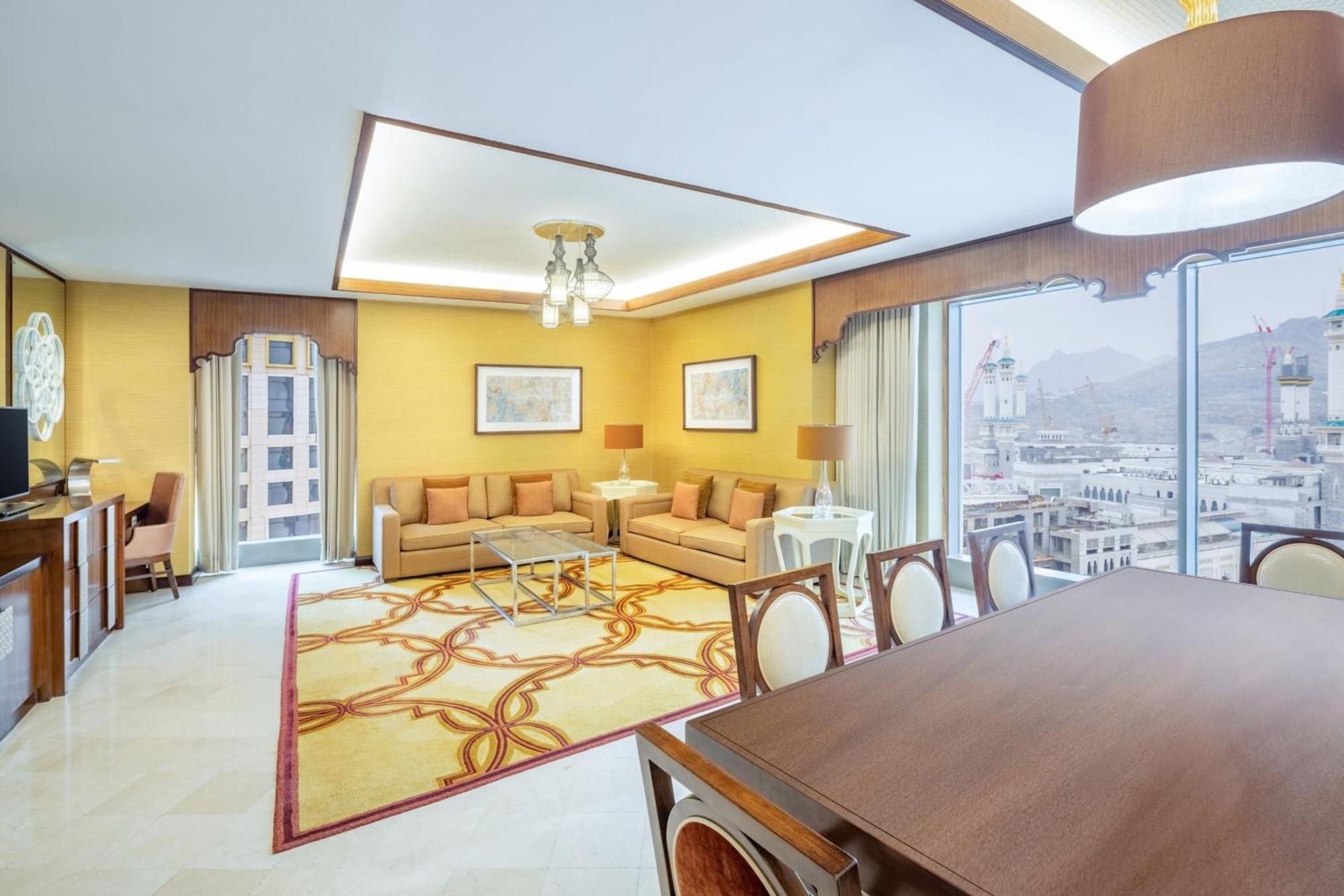 Jabal Omar Marriott Hotel Makkah Mecca Екстер'єр фото The photo shows a spacious and elegantly designed living area. The walls are painted in a warm yellow shade, complemented by large windows that provide plenty of natural light and a view of the outside. 

In the center, there's a seating area with a 