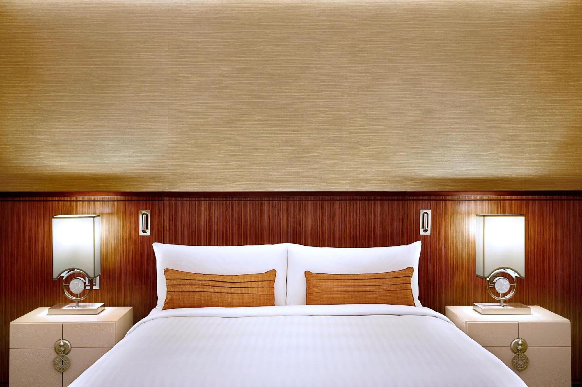 Jabal Omar Marriott Hotel Makkah Mecca Екстер'єр фото The photo shows a well-designed hotel room, focusing on a stylish bed with a simple yet elegant aesthetic. The bed is dressed in white linens and has two decorative pillows in a warm, golden color. Behind the bed is a smooth, light-colored wall, addi